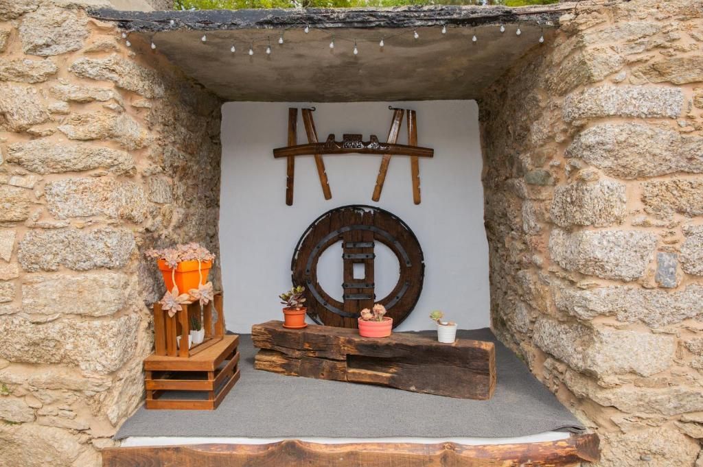 Nicho rústico de piedra con herramientas de madera en miniatura, una rueda y una pequeña exhibición de llamas en su interior.