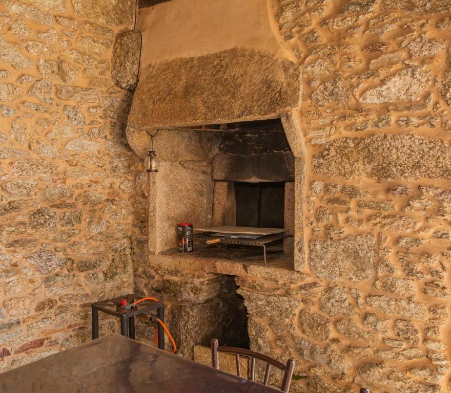 Chimenea de piedra con horno empotrado en una pared de mampostería rústica.