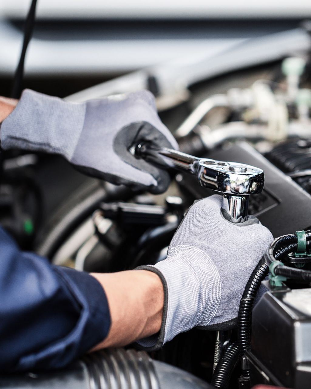 Personne avec des gants qui serre un élément de mécanique