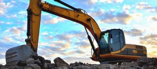 Una excavadora amarilla está moviendo rocas en un sitio de construcción.