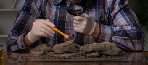 Un hombre mira a través de una lupa una pila de rocas.