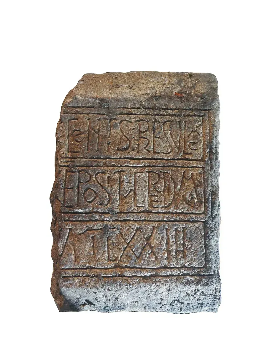 Un bloque de piedra con letras talladas sobre un fondo blanco.