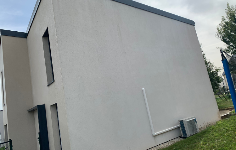 Un bâtiment blanc avec un toit noir se trouve au sommet d'un champ vert luxuriant.