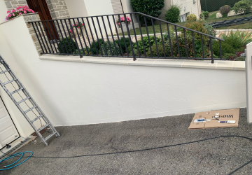 Une échelle est posée sur le sol devant un mur blanc.