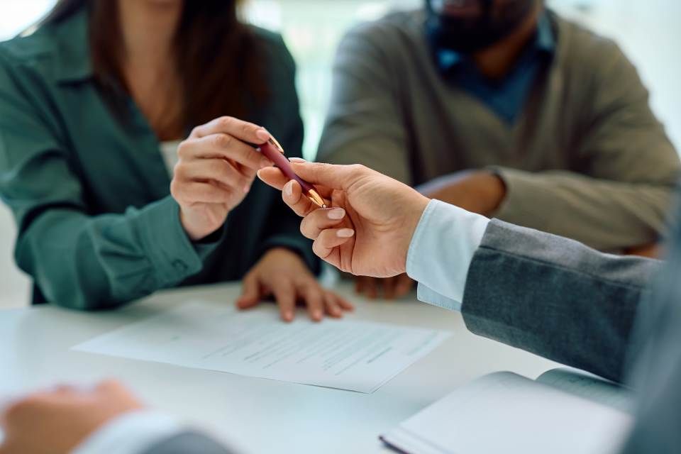 Ein Mann und eine Frau sitzen an einem Tisch und unterschreiben ein Dokument.