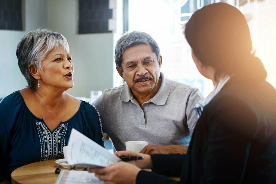Ein Mann und eine Frau sitzen an einem Tisch und unterhalten sich mit einer Frau.