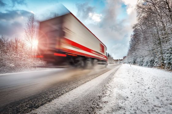 Un camión semirremolque circula por una carretera nevada.