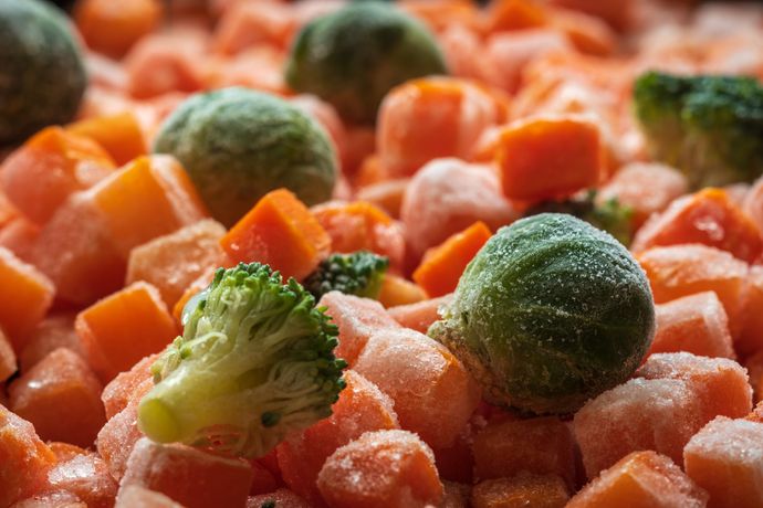 Una pila de verduras congeladas, incluidas zanahorias, brócoli y coles de Bruselas.