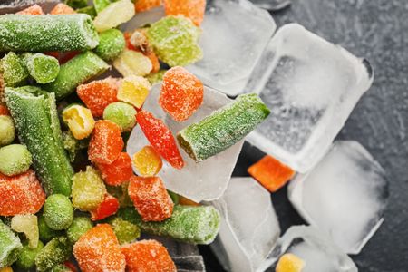 Una pila de verduras congeladas encima de cubitos de hielo.