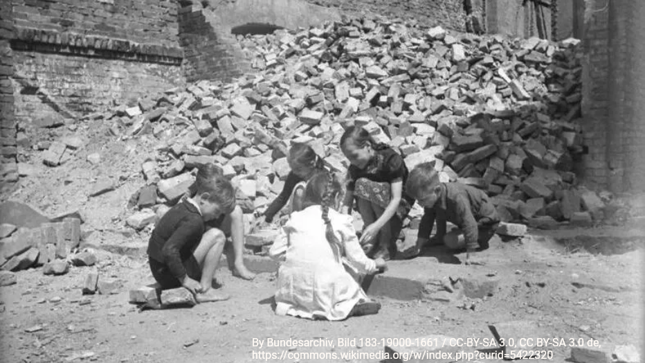 Warum ich über die Nachkriegsgeneration schreibe Kriegstraumata enden nicht mit dem Schweigen der Waffen. Sie wirken weiter. Über Generationen hinweg. Kinder spielen auf dem Boden vor einem großen Haufen Ziegelsteinschutt inmitten von Gebäuderuinen.