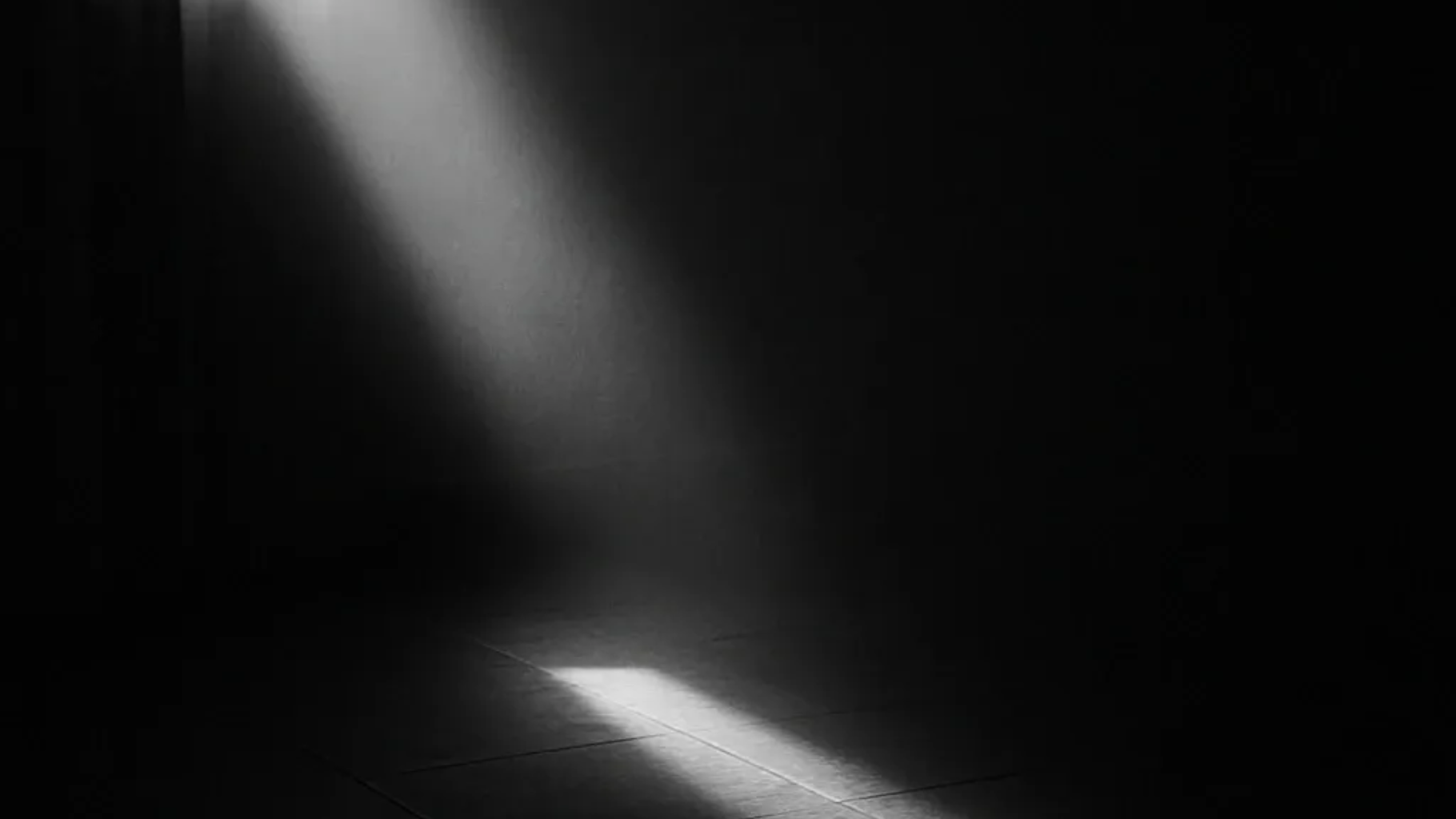 Ein Lichtstrahl scheint durch einen dunklen Raum und beleuchtet einen kleinen Fleck auf dem Boden.