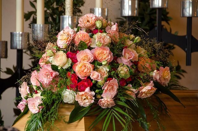 Buntes Blumenarrangement aus Rosen und Grünpflanzen, dekorativ angeordnet, symbolisiert einen würdev