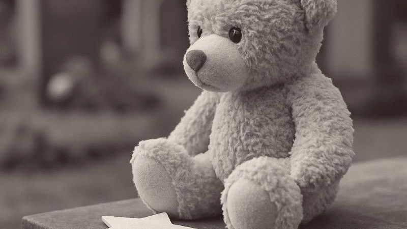 Schwarzweißbild eines Teddybären, der allein dasitzt und nachdenklich dreinschaut