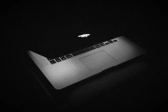 Ein Laptop auf einer dunklen Oberfläche, dramatisch in Schwarz-Weiß beleuchtet.