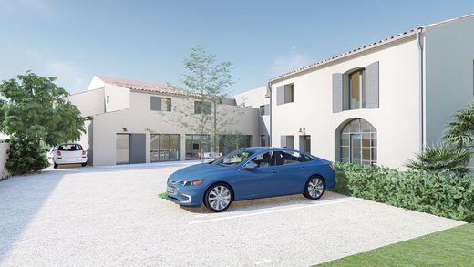 Maisons blanches modernes avec une voiture bleue garée dans une allée lumineuse.