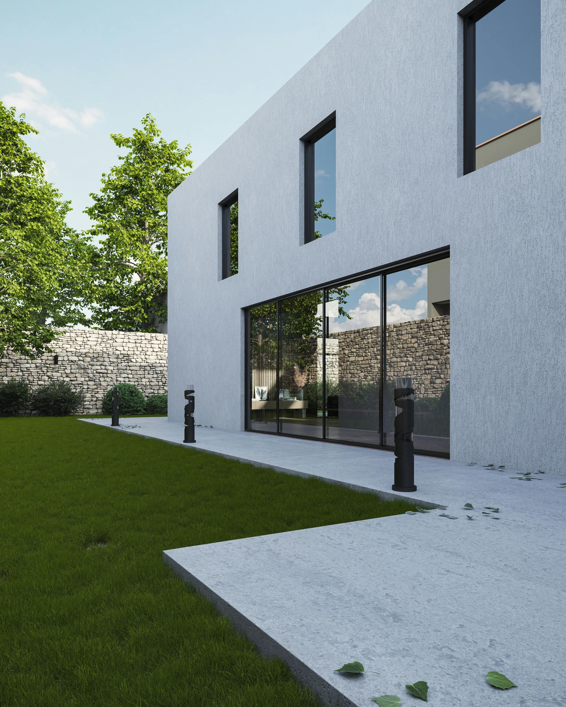 Extérieur d'une maison blanche moderne avec de grandes portes vitrées, pelouse verte et terrasse en pierre ensoleillée