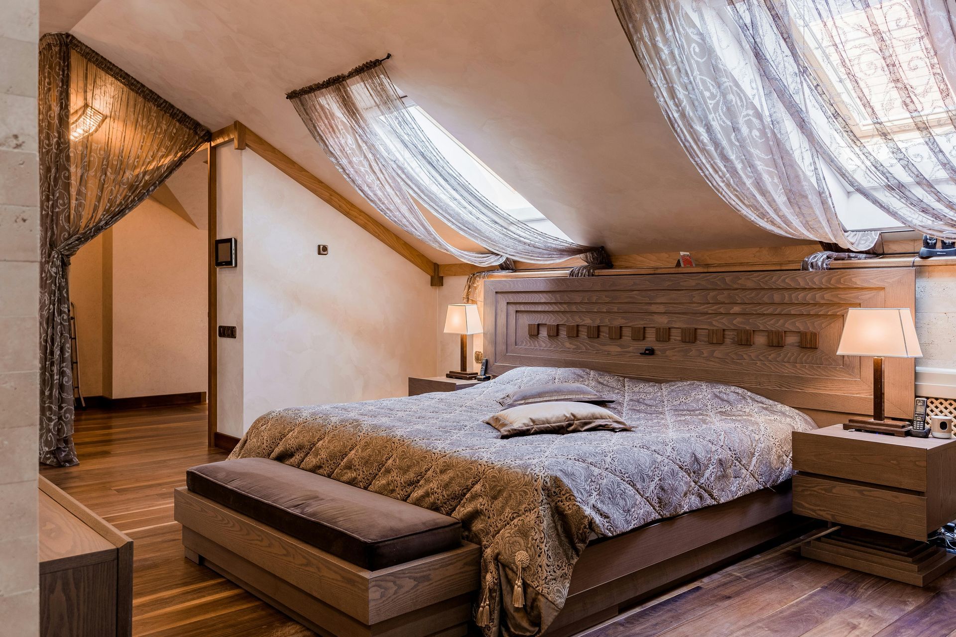 Chambre confortable avec plafond mansardé, rideaux à baldaquin, meubles en bois et éclairage doux et chaleureux