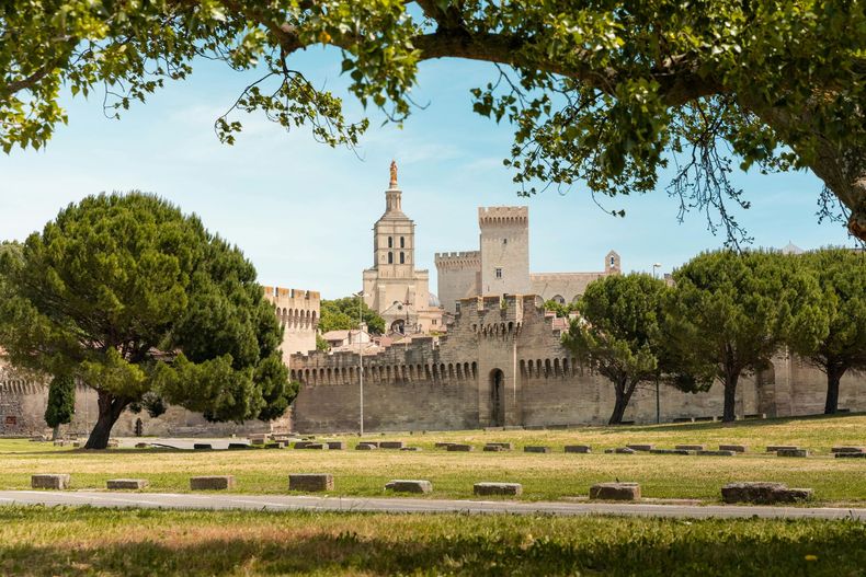 Cathédrale de pierre et remparts de forteresse derrière les arbres dans un parc ensoleillé sous un ciel bleu limpide