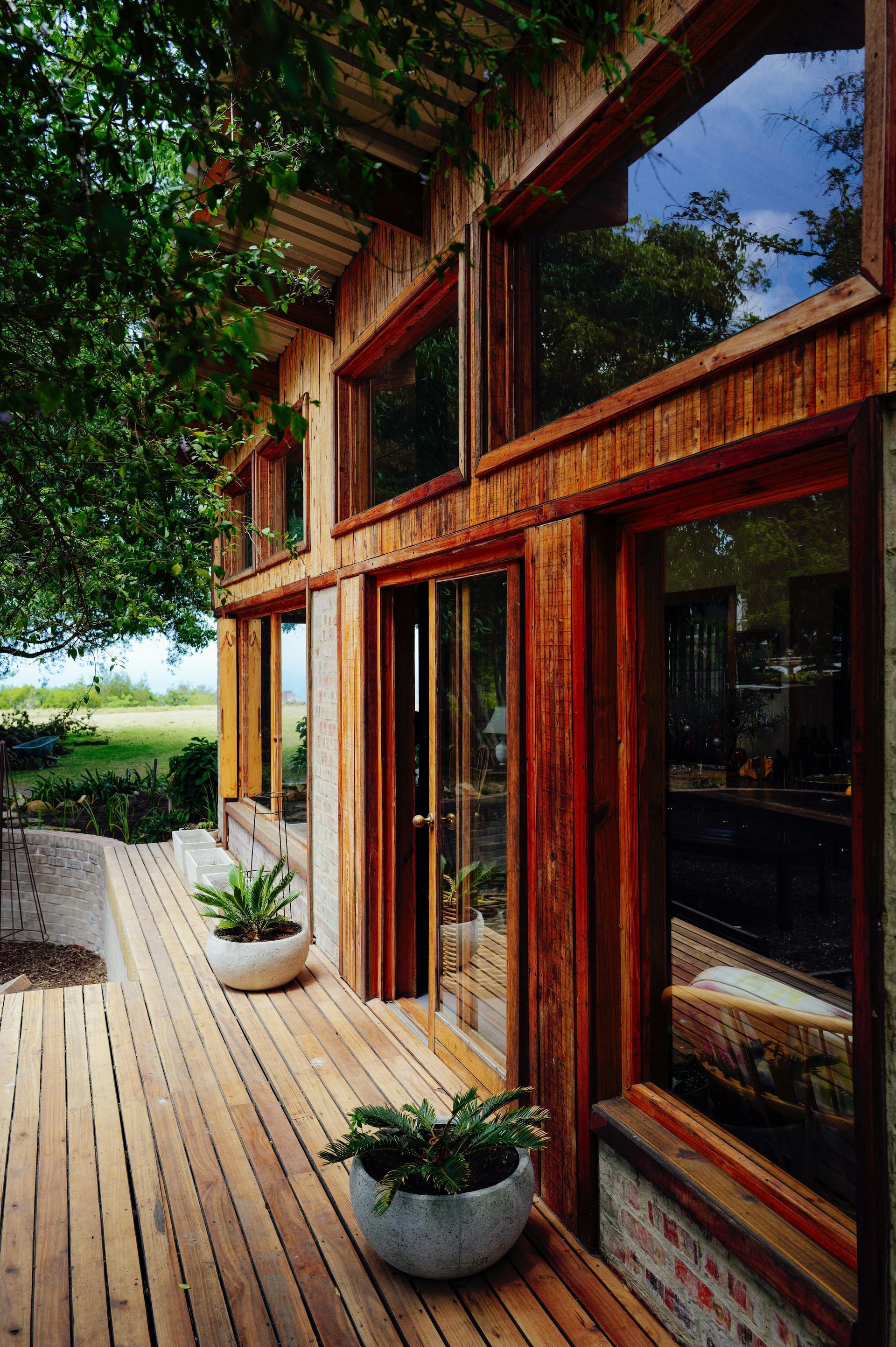 Terrasse en bois jouxtant une maison moderne en verre et en bois.