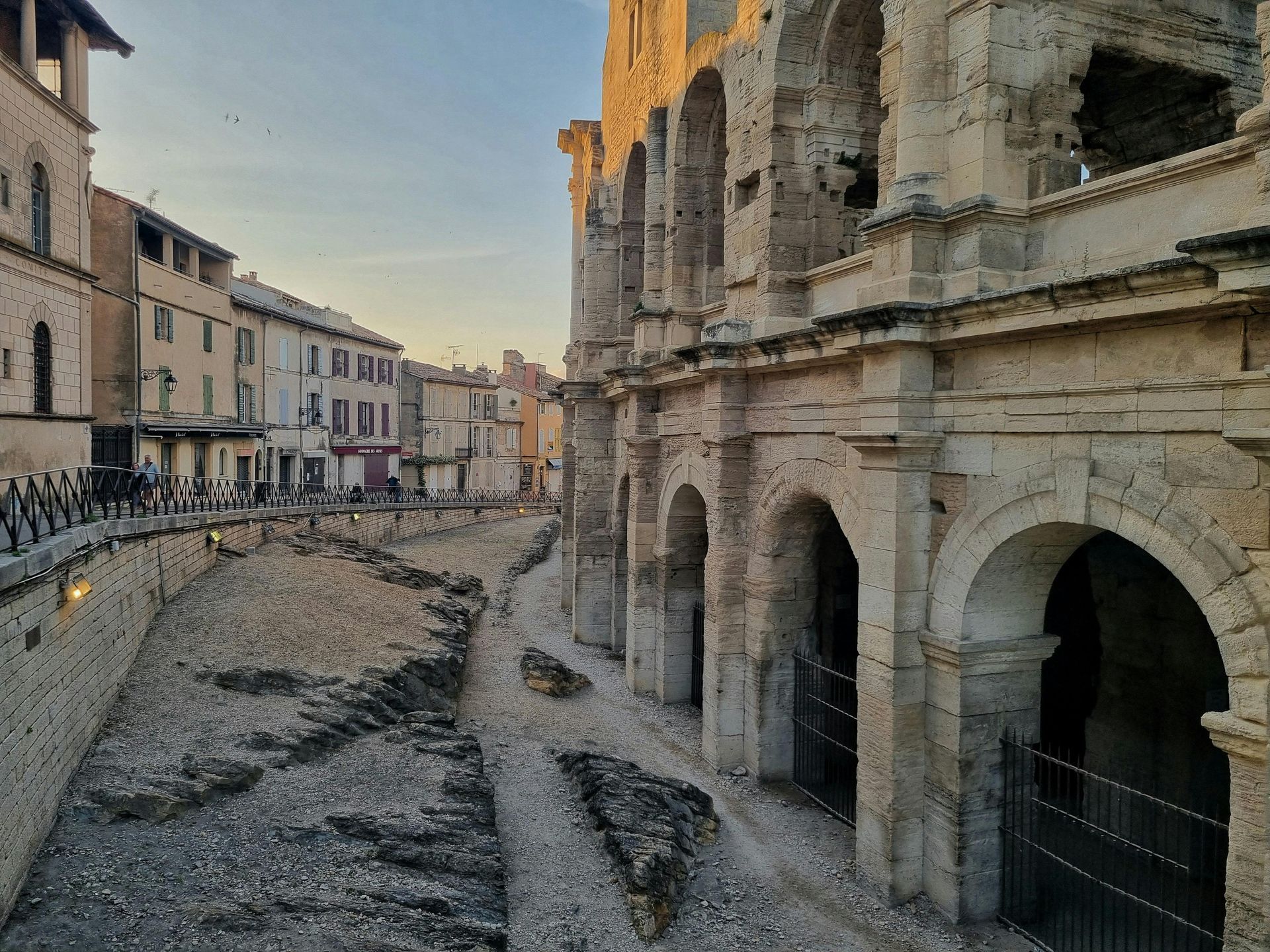 Ruines d'un ancien amphithéâtre en pierre au bord d'une rue pavée au coucher du soleil