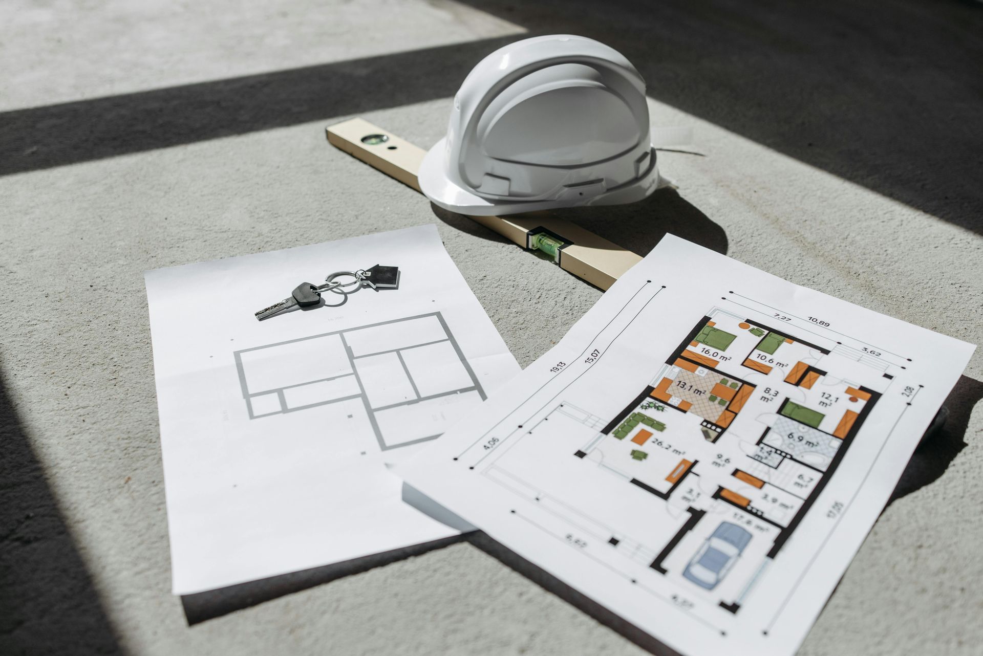 Plans d'étage et un casque de chantier sur une surface en béton ensoleillée