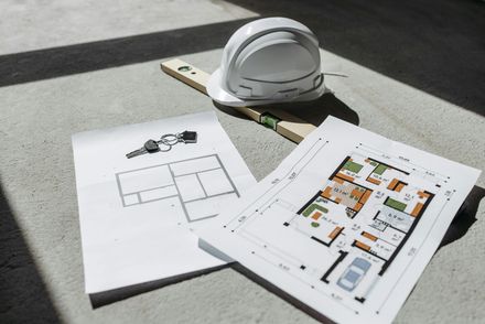 Plans d'étage et un casque de chantier sur une surface en béton ensoleillée