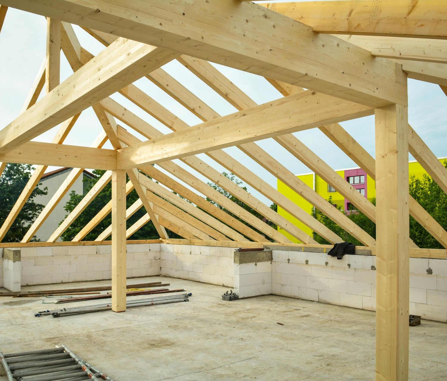 Charpente de toit en bois en cours de construction sur une ossature de bâtiment sur un site inachevé.