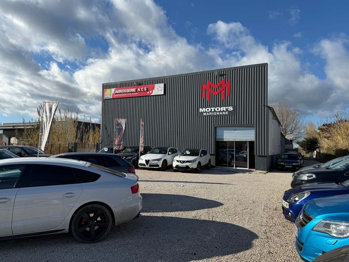 Voiture de sport Porsche argentée avec des accents noirs et vert fluo, garée à l'extérieur.