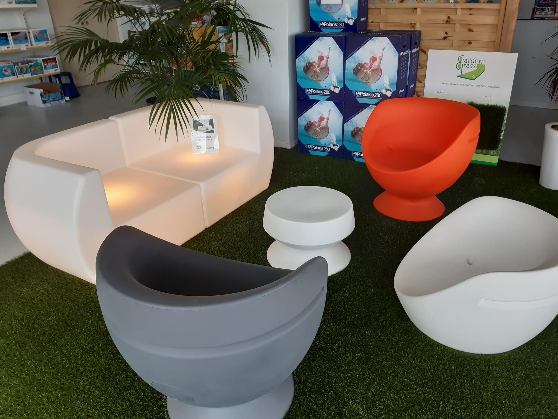 Une femme et un homme consultent des papiers dans un magasin. Herbe verte, chaises et accessoires de piscine.