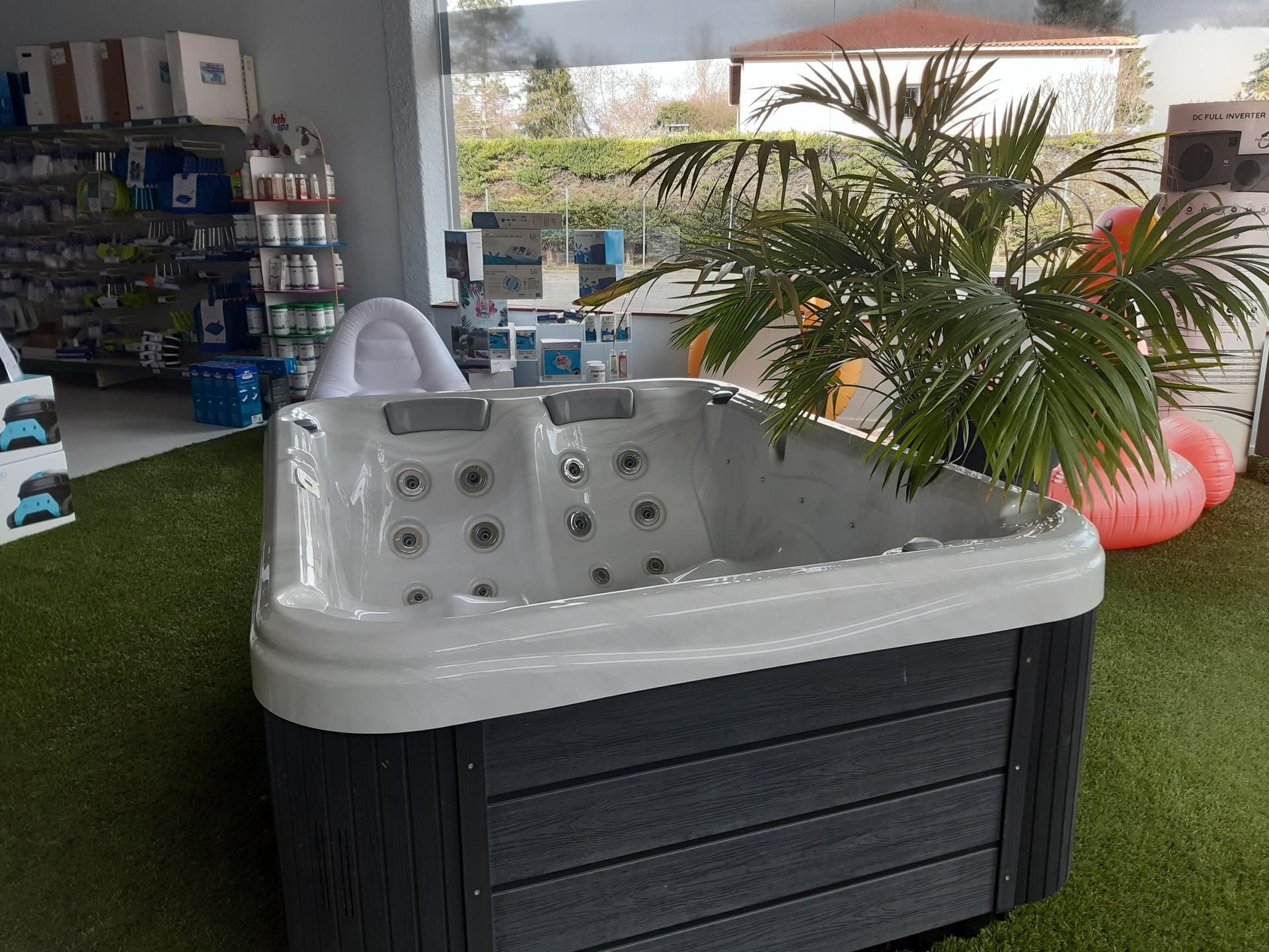 Un spa noir et gris exposé dans un magasin, avec une plante et d'autres produits.