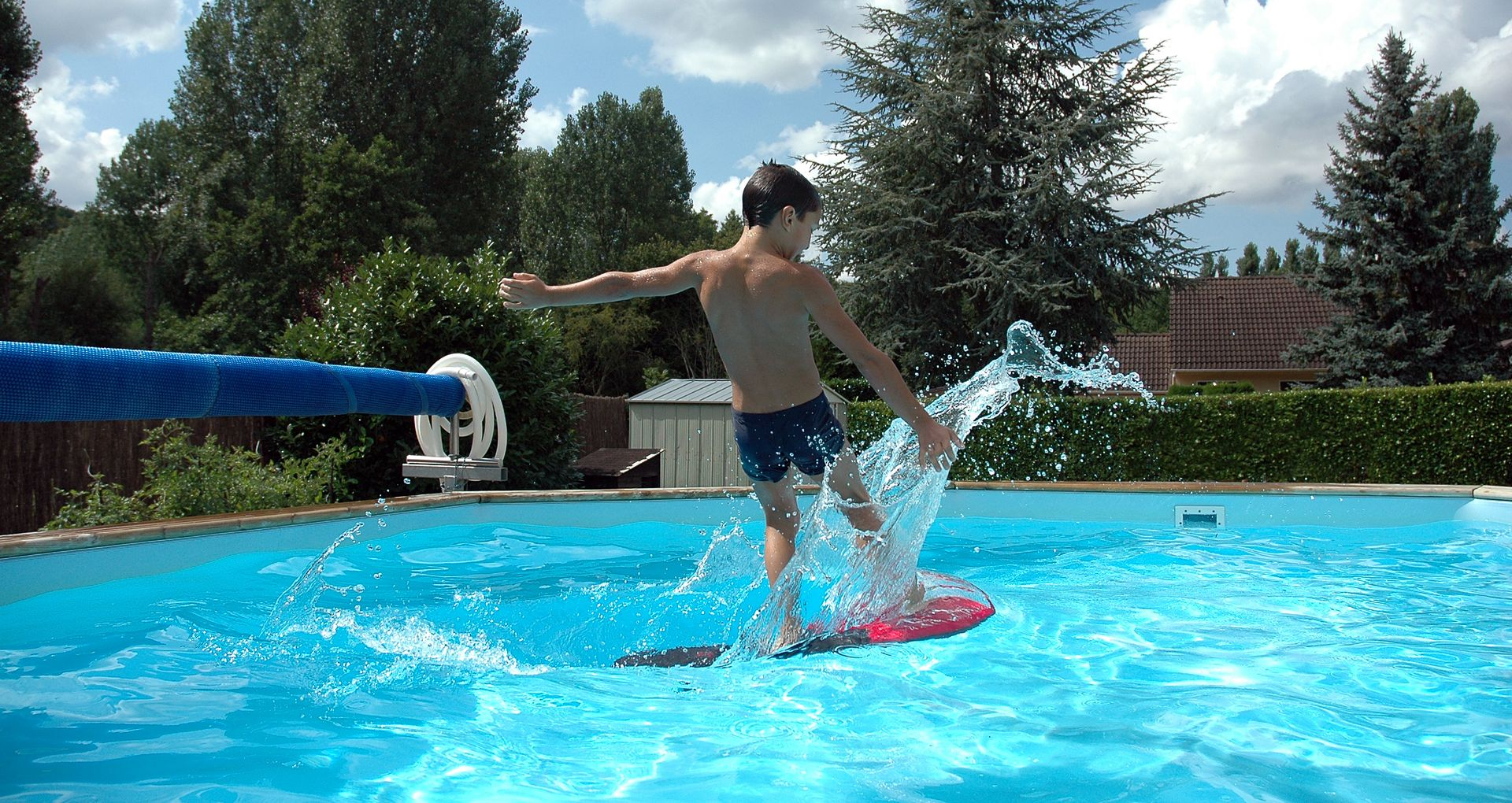 Un système de filtration de piscine avec des tuyaux blancs et une pompe noire est posé sur l'herbe.
