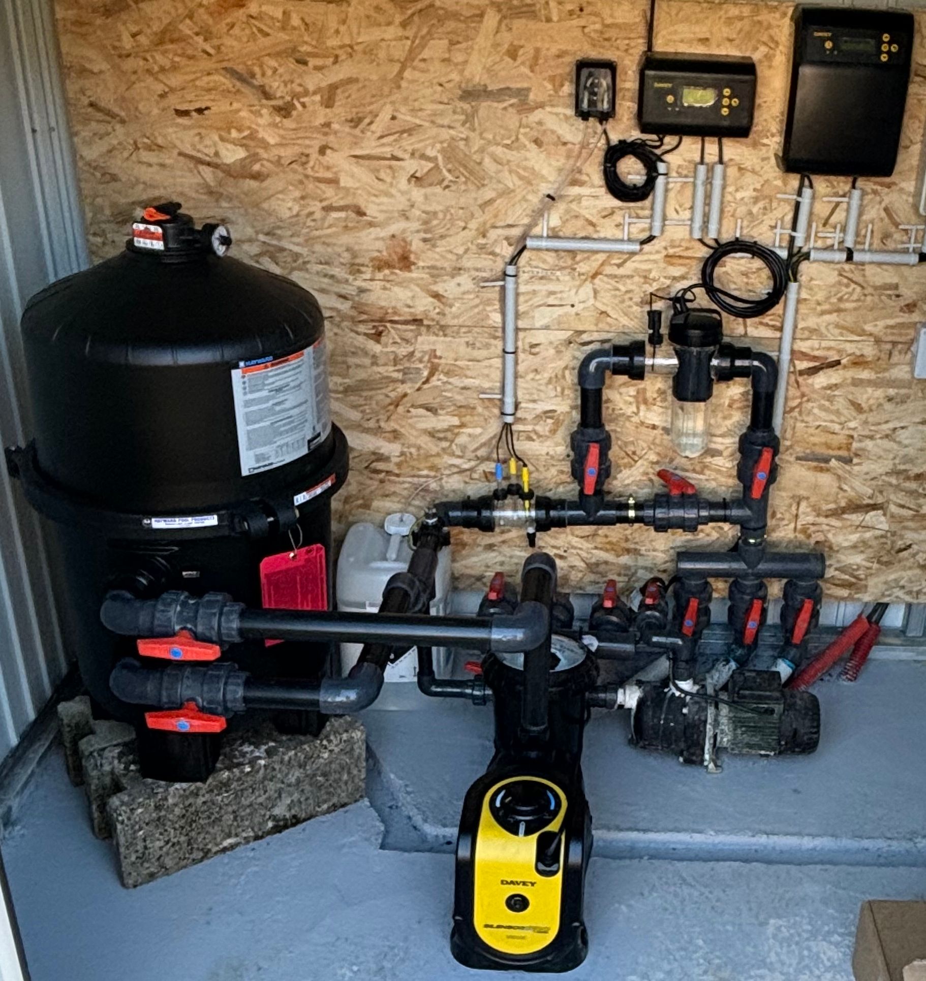 Système de filtration de piscine dans un boîtier encastré à côté d'une piscine.