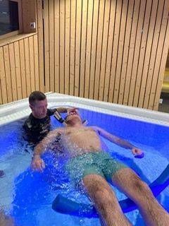 Un homme est allongé dans une piscine er reçoit des soins.