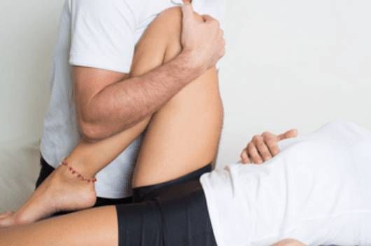 Un homme étire la jambe d'une femme sur une table.