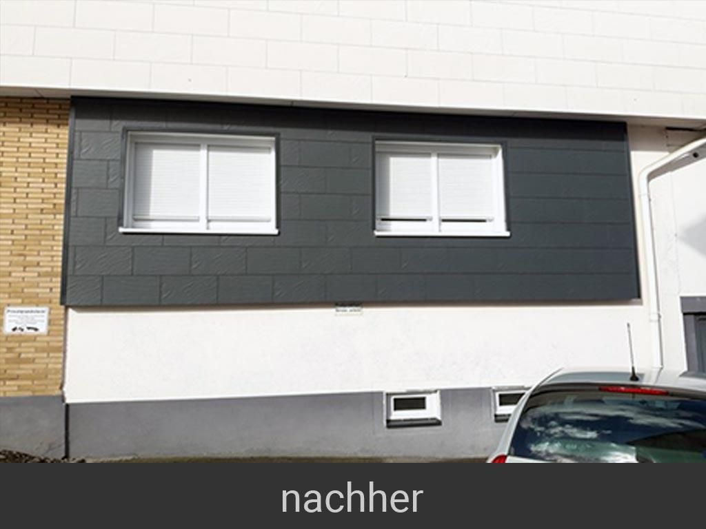 Vor einem Gebäude mit zwei Fenstern parkt ein Auto.