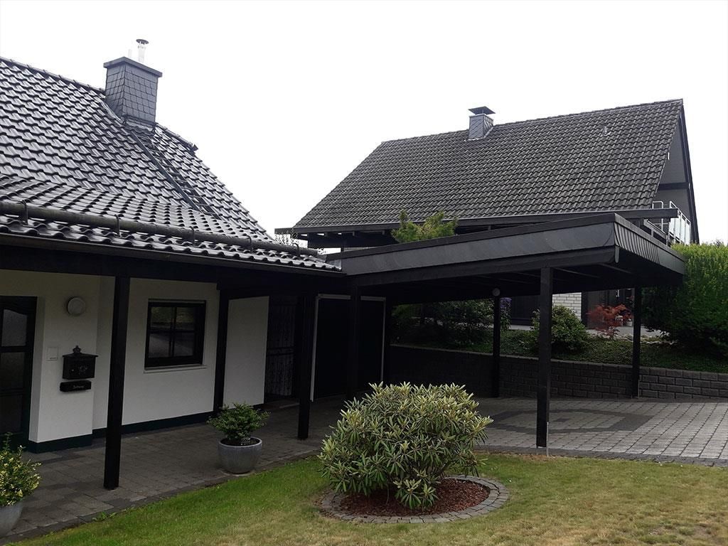 Ein Haus mit Veranda und davor einem Carport