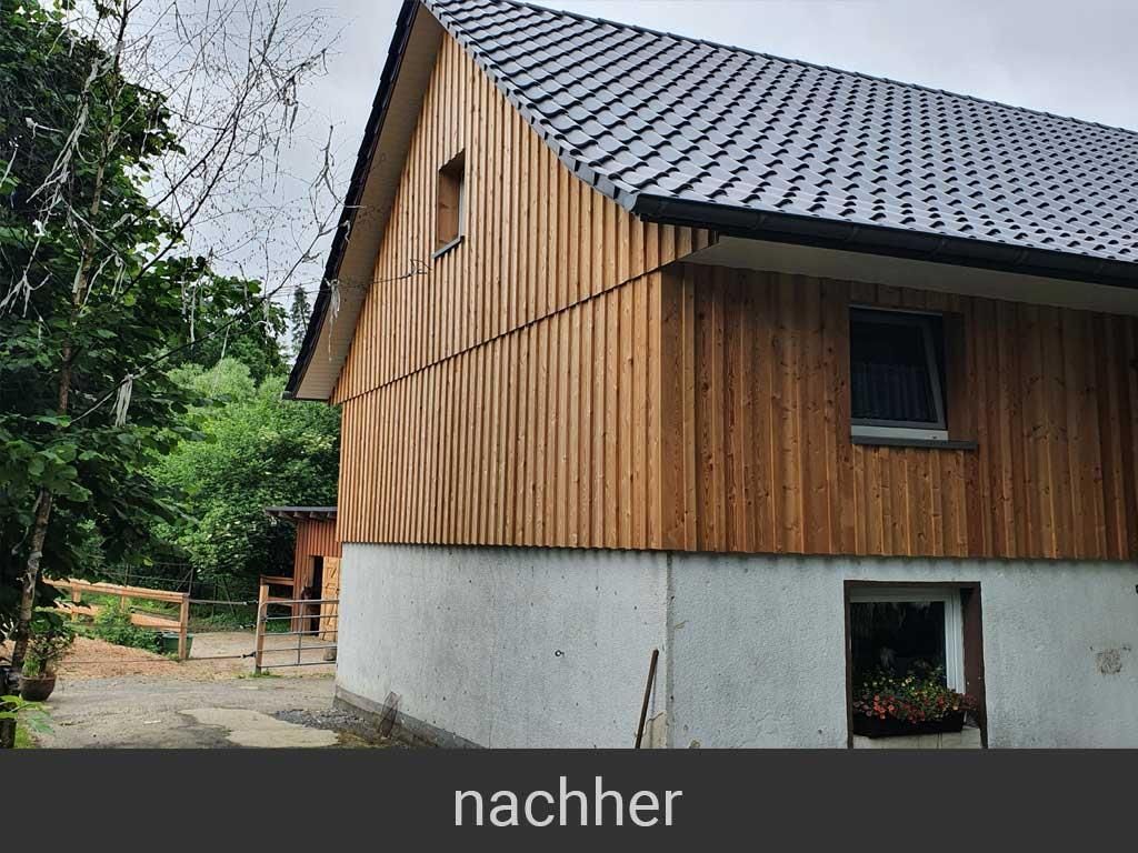 Ein Haus mit Holzverkleidung und schwarzem Dach