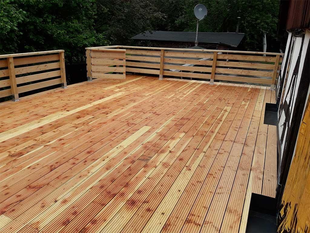 Ein Holzdeck mit einem Zaun und einer Satellitenschüssel darauf.