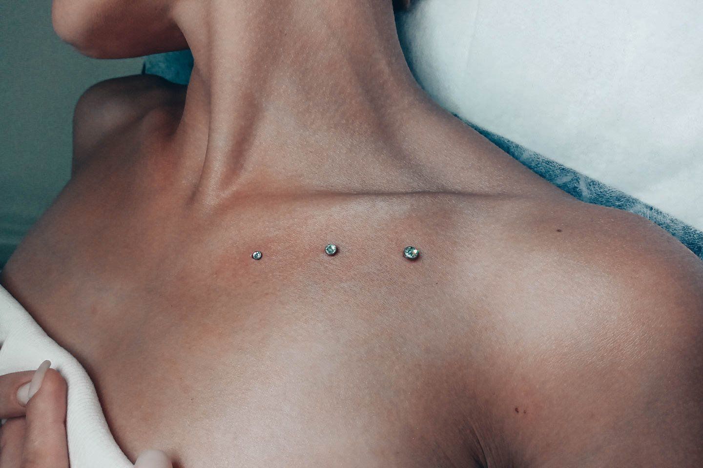 Un primer plano del pecho de una mujer con tres piercings.