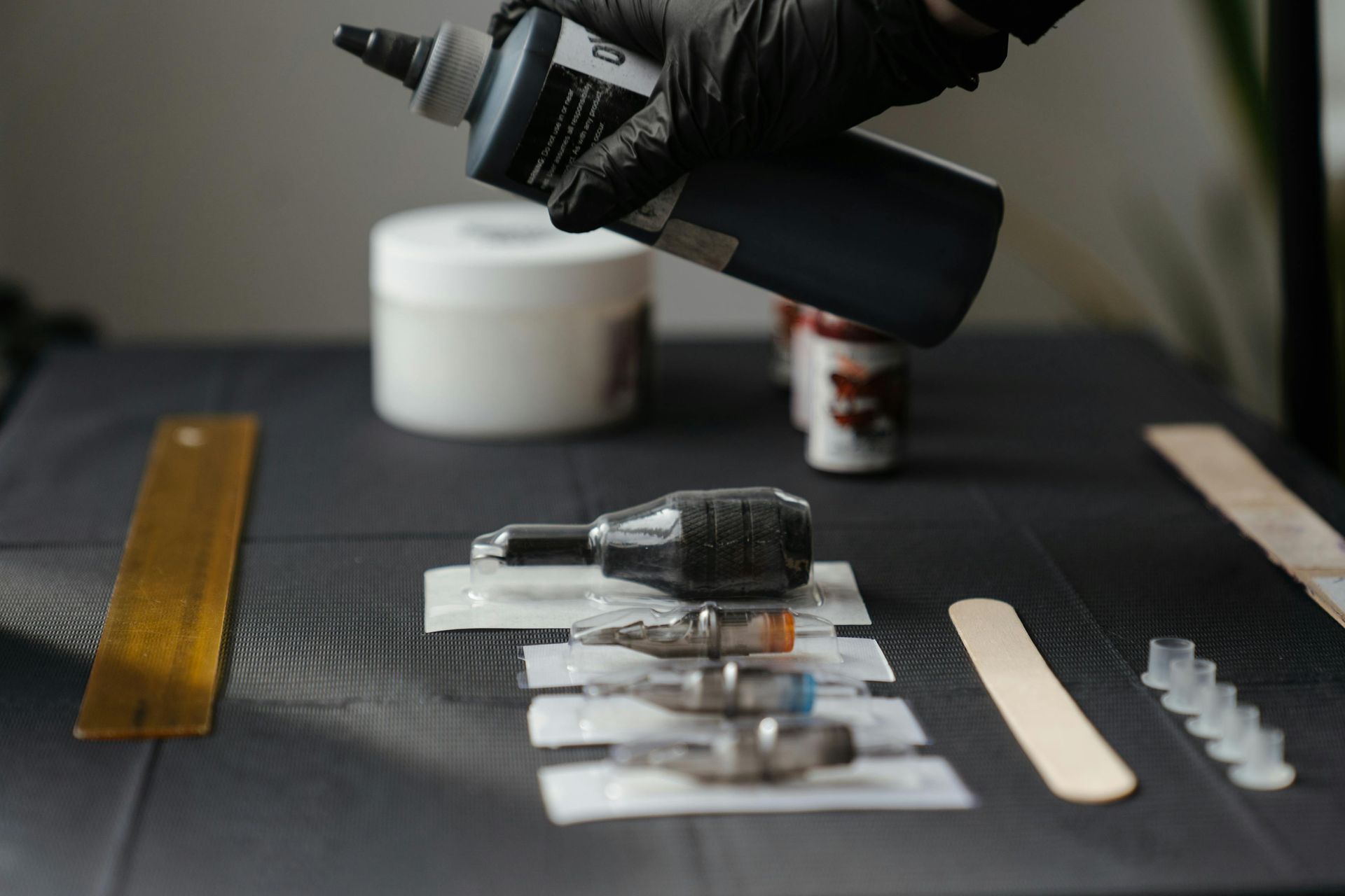 Una persona está vertiendo líquido en una máquina de tatuajes sobre una mesa.