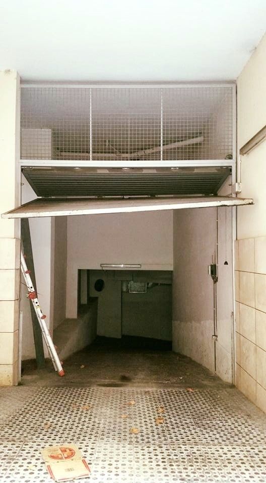 Muelle de carga con puerta metálica abierta y rampa. Paredes blancas y espacio de servicio visible en el interior.