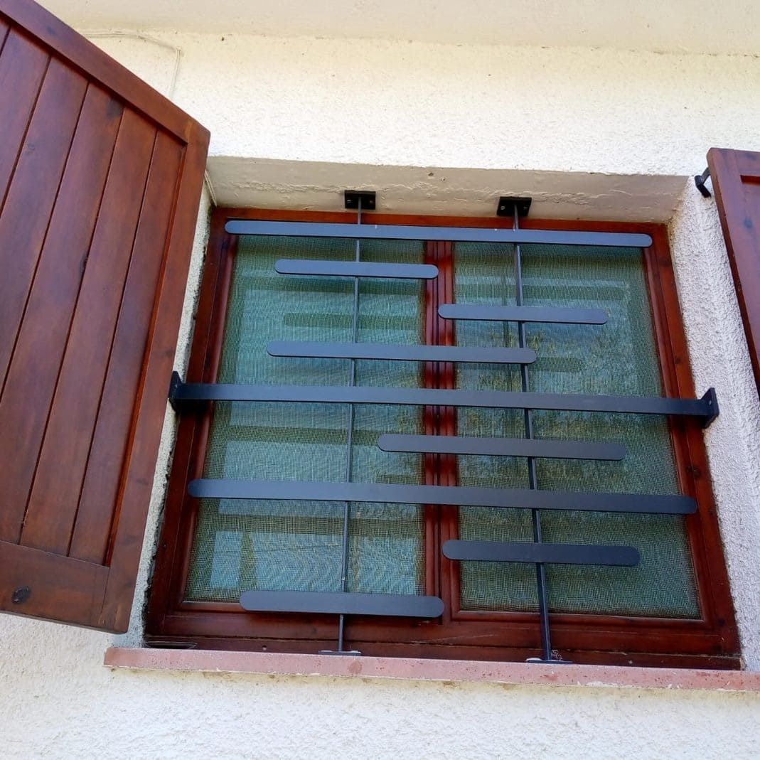 Ventana con persianas marrones y rejas de seguridad.