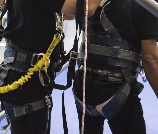 Dos personas con arneses de seguridad conectados a cuerdas, probablemente para escalar o rescatar.