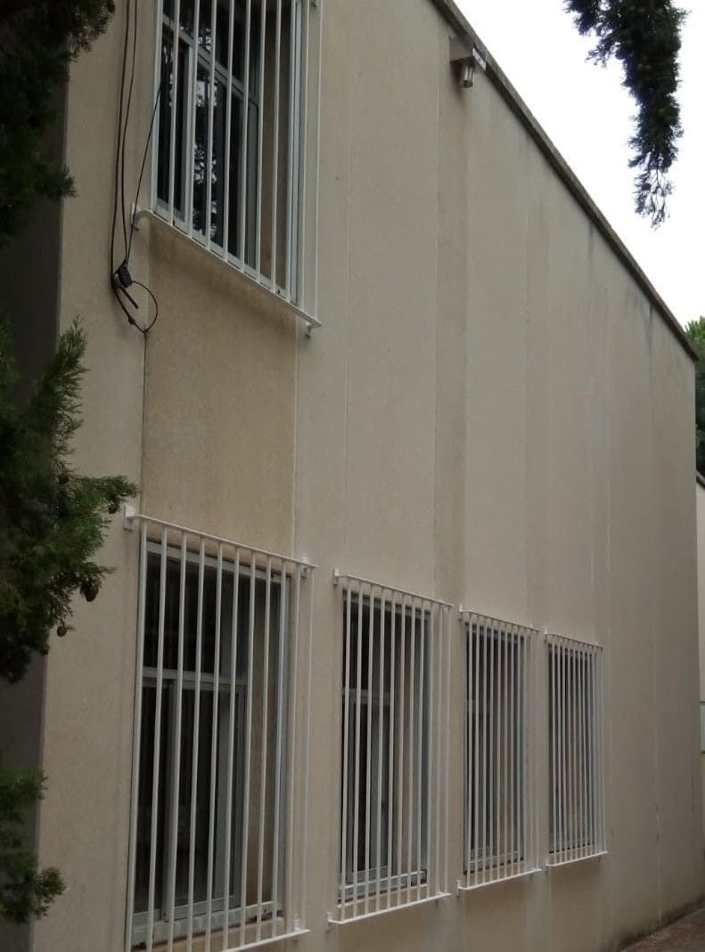 Edificio de color beige con varias ventanas enrejadas.