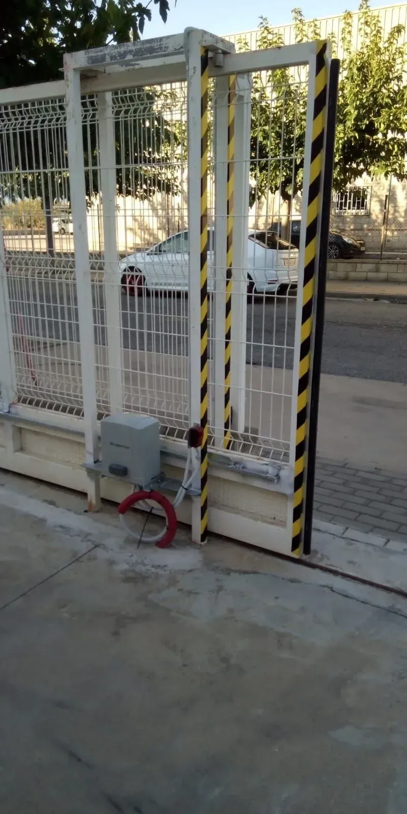 Una puerta corredera metálica blanca con franjas diagonales negras y amarillas está abierta.