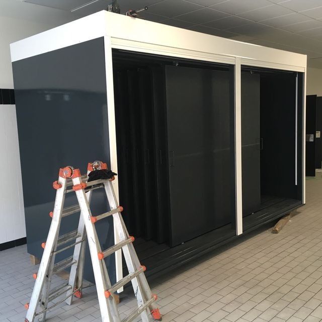 Mueble de almacenaje de color gris y blanco con puertas correderas, en el frente hay una escalera.