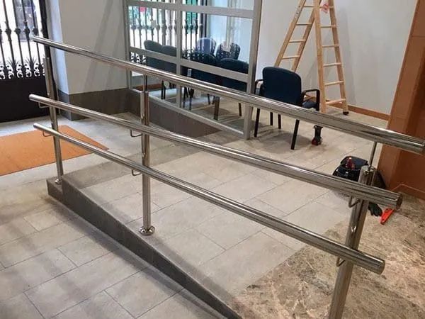 Barras paralelas de acero inoxidable con rampa para accesibilidad.