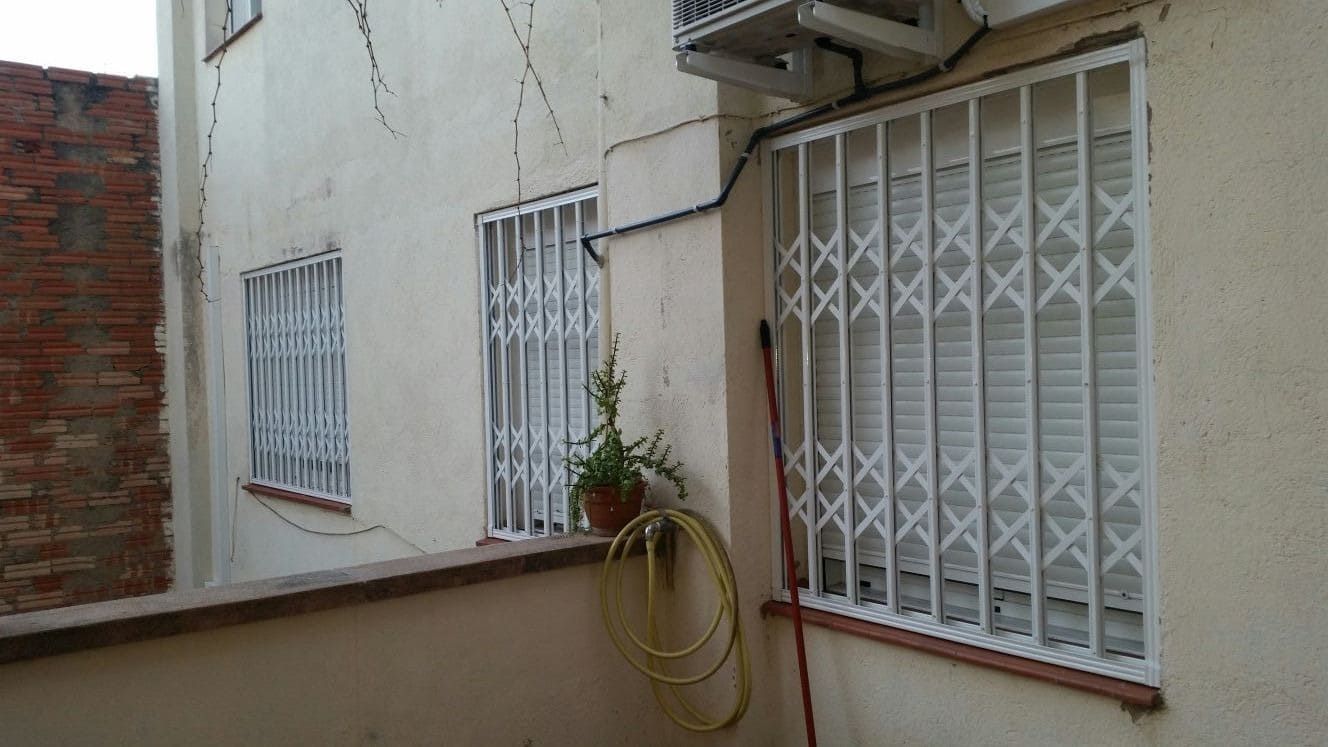 Edificio exterior con tres ventanas, cada una protegida con rejas blancas. 
