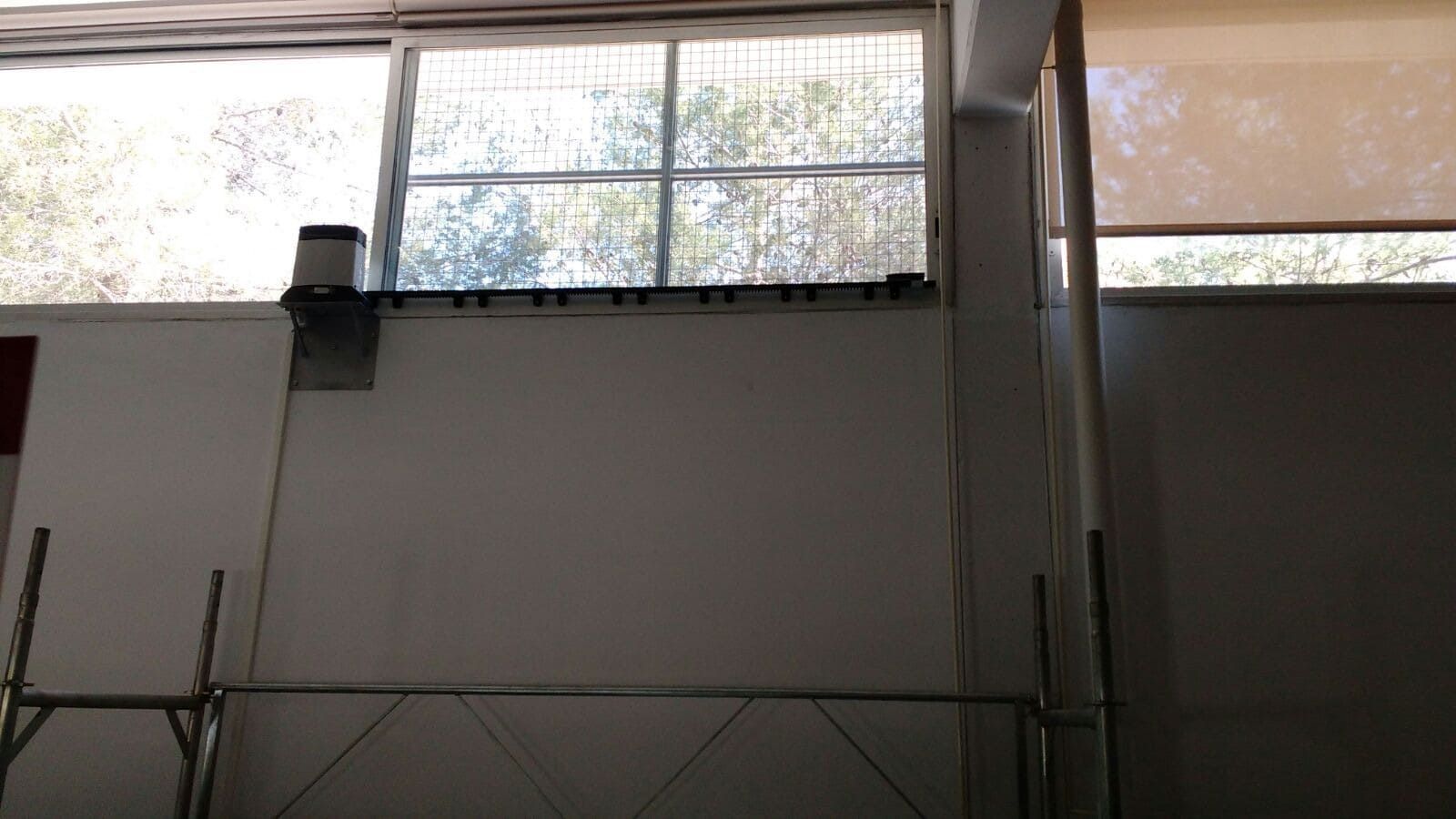 Vista interior de un edificio con ventanas, una viga de soporte y un andamio.