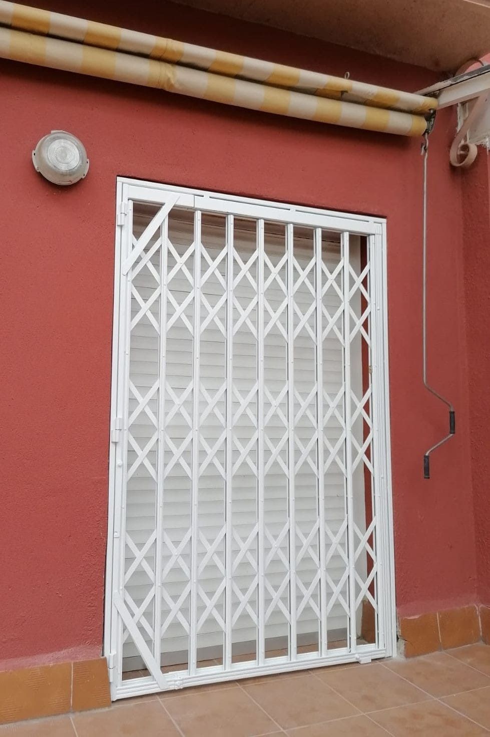 Puerta de seguridad blanca en un edificio rojo.
